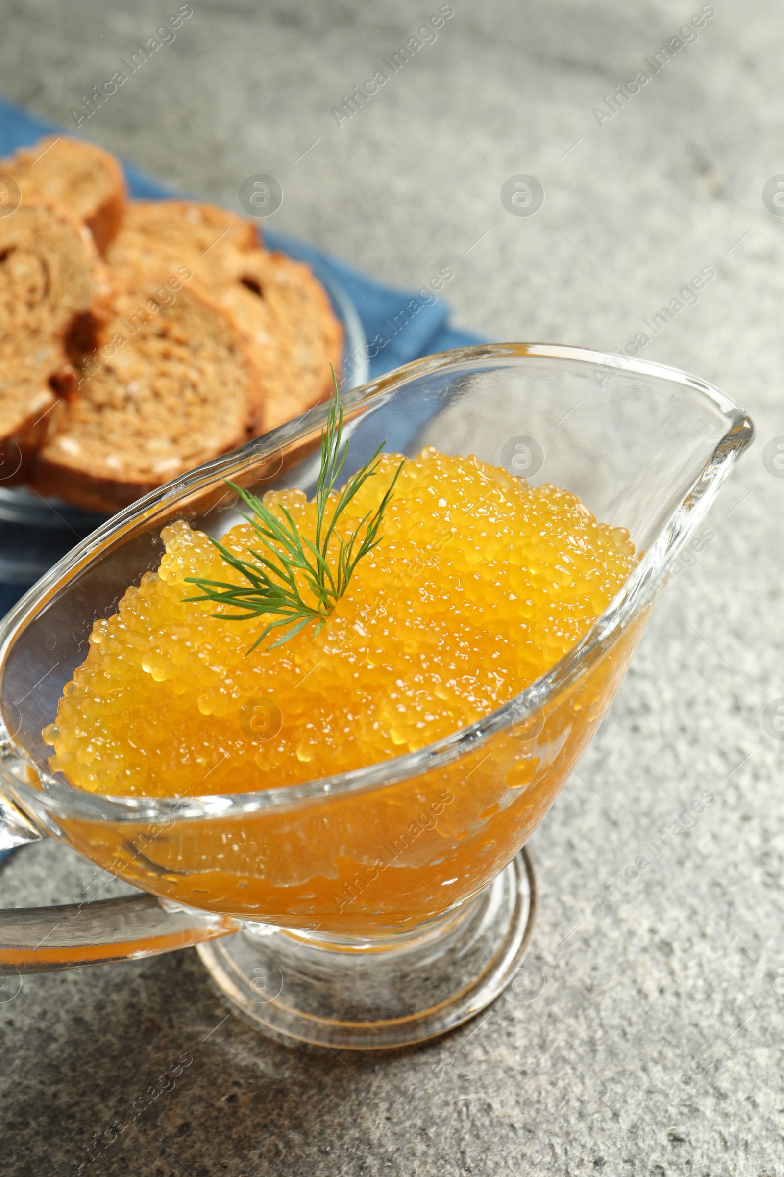 Photo of Fresh pike caviar and dill in gravy boat on grey table, closeup