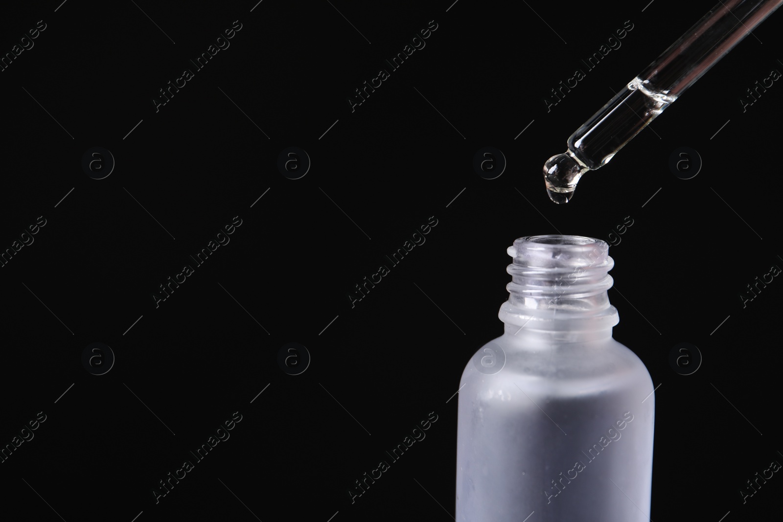 Photo of Dripping cosmetic serum from pipette into bottle on black background, space for text