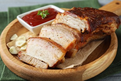 Photo of Pieces of baked pork belly served with sauce on table, closeup