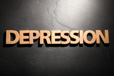 Word Depression made of wooden letters on black table, flat lay