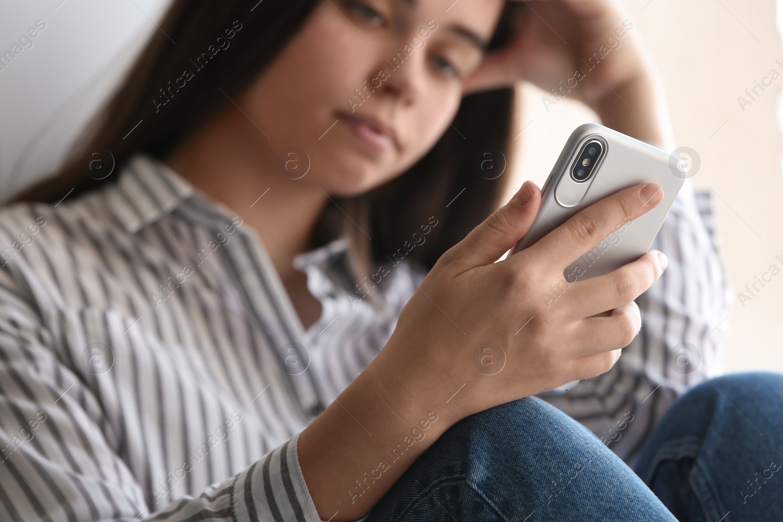 Photo of Young woman holding mobile phone on light background, closeup with space for text. Loneliness concept