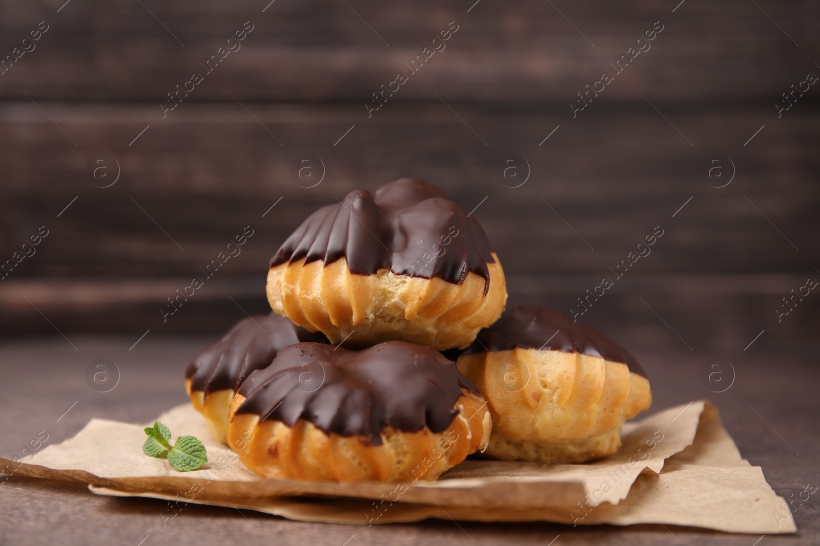 Photo of Delicious profiteroles with chocolate spread and mint on table, closeup