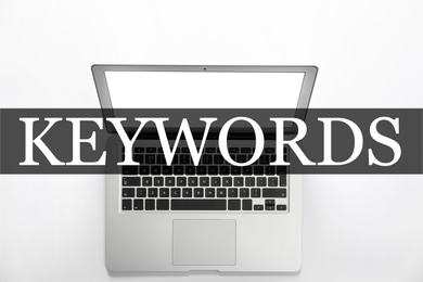 Image of Word Keywords and laptop on white background, top view. SEO direction