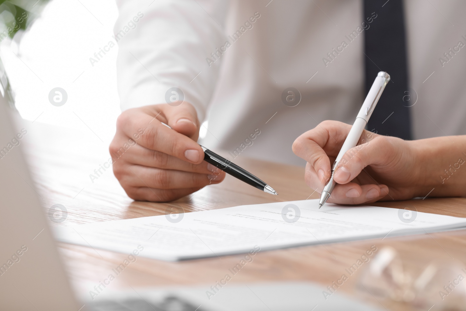 Photo of Businesspeople signing contract at table in office, closeup