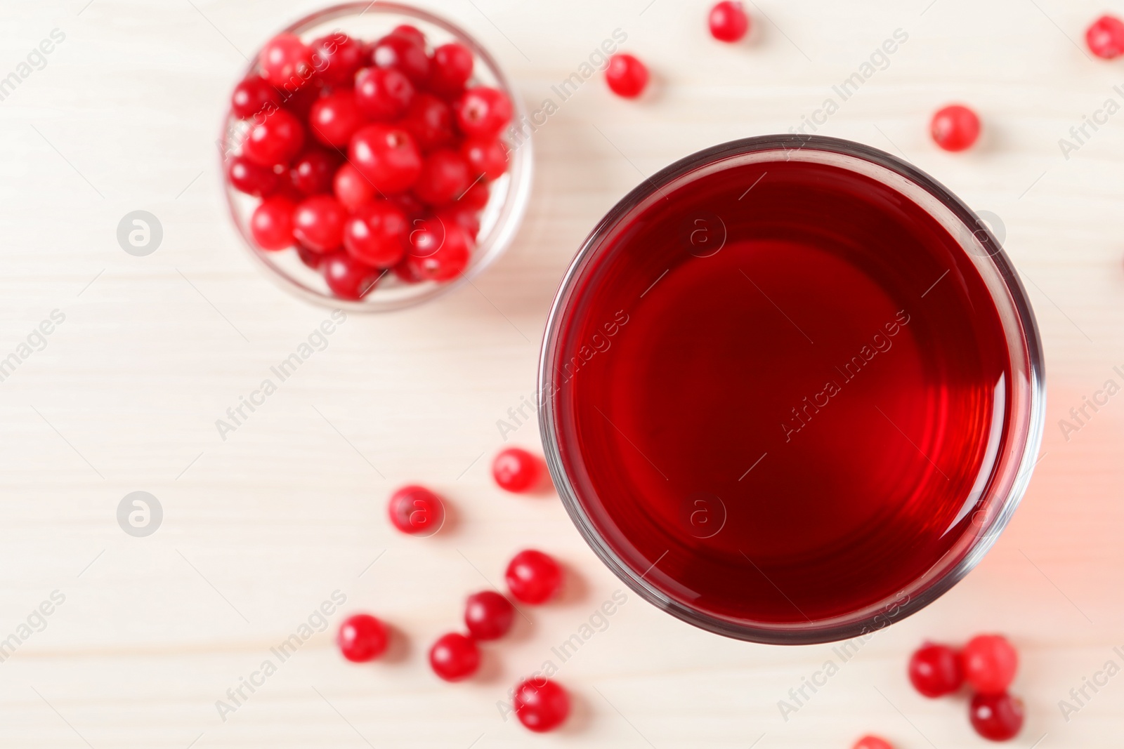 Photo of Tasty cranberry juice in glass and fresh berries on white wooden table, flat lay. Space for text