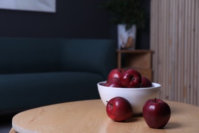 Red apples on wooden coffee table in room