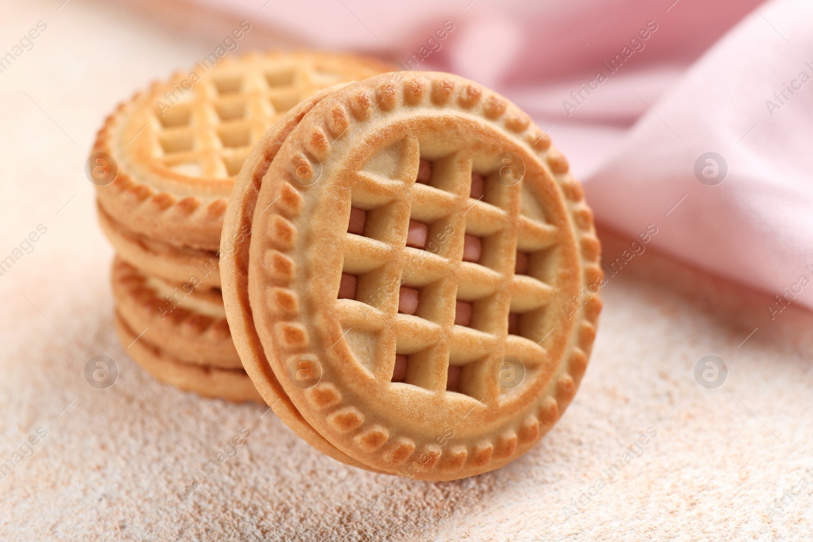 Photo of Tasty sandwich cookies with cream on beige background, closeup