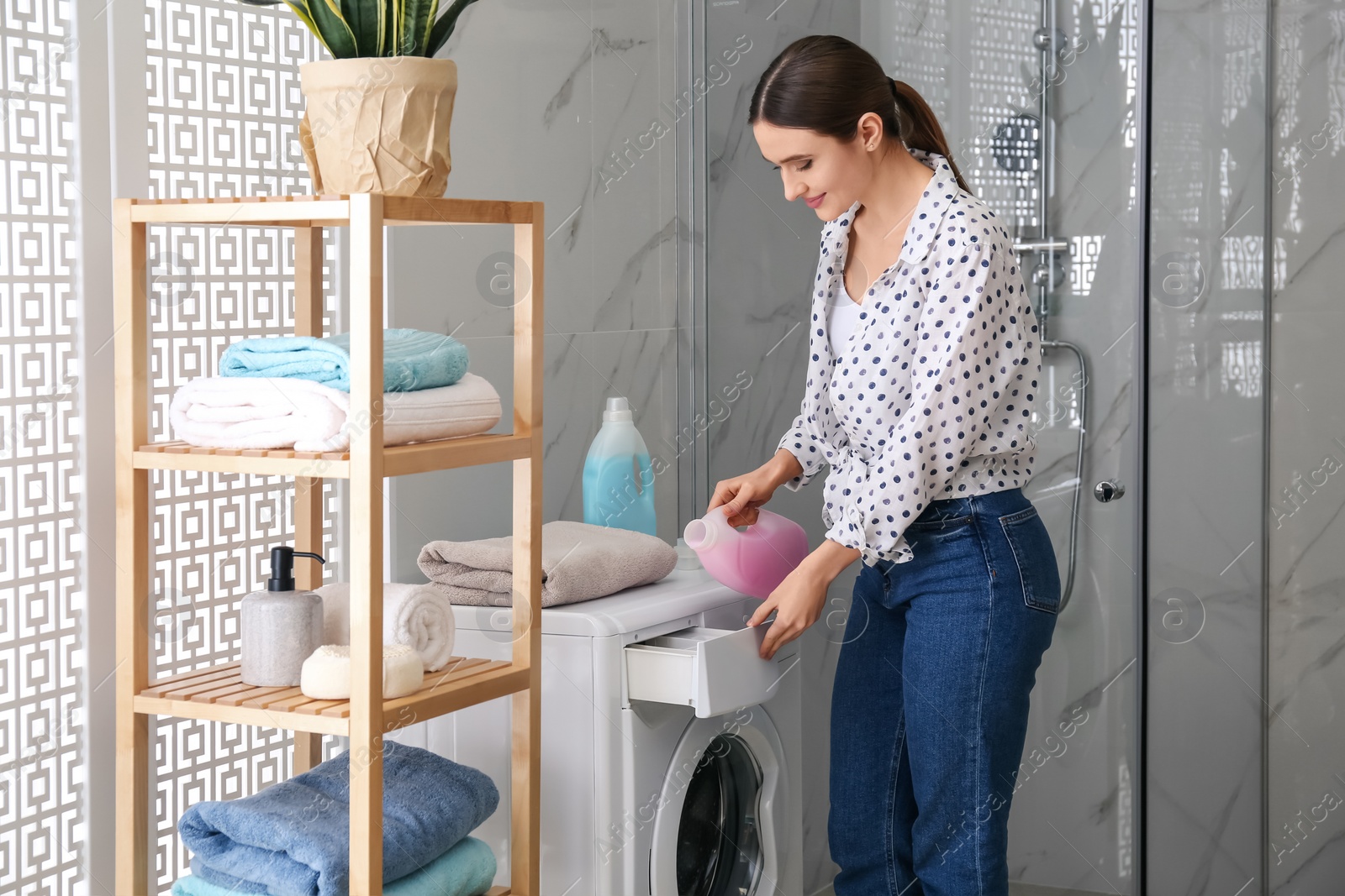 Photo of Woman pouring detergent into washing machine drawer in bathroom. Laundry day