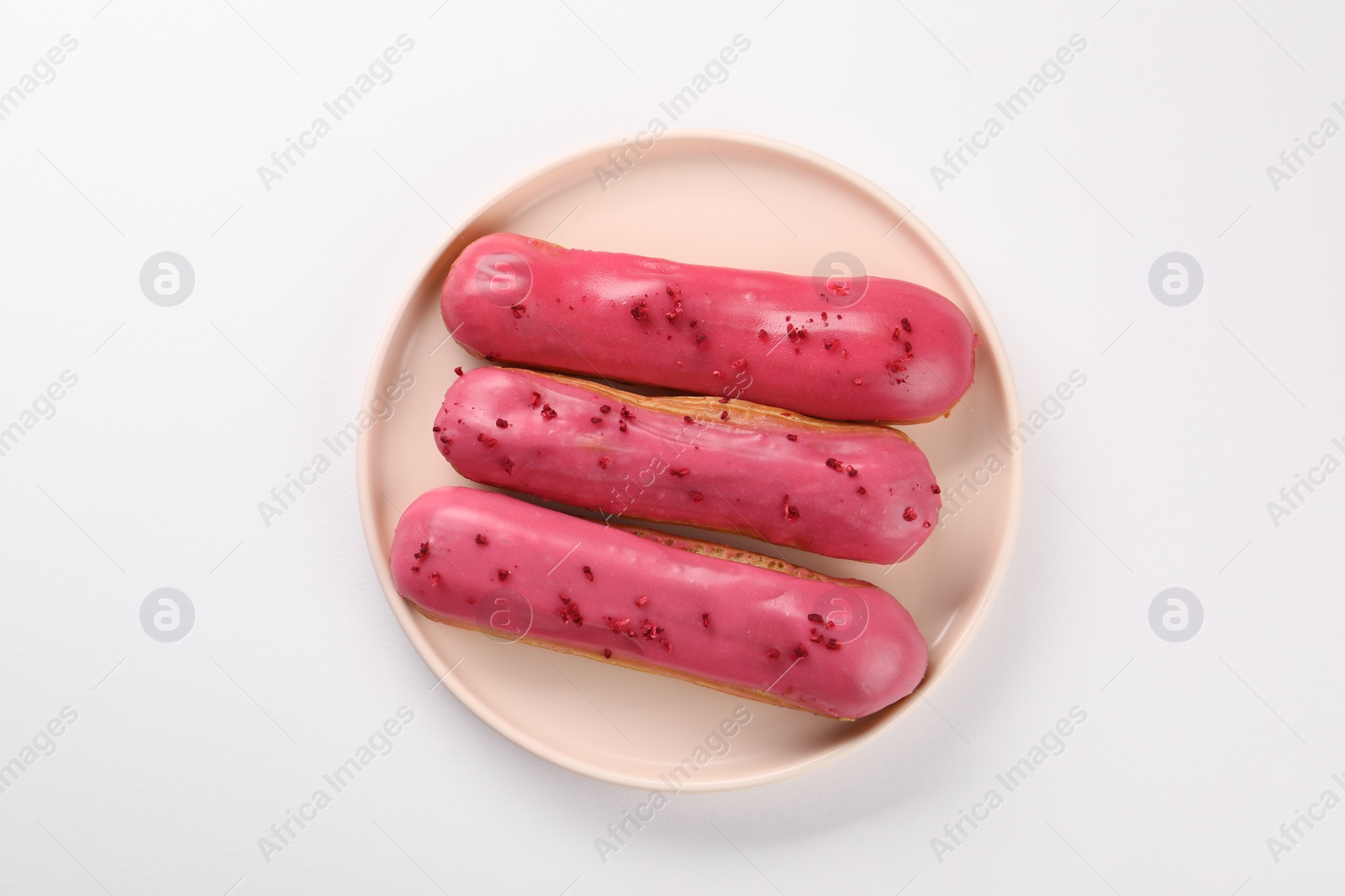 Photo of Delicious eclairs covered with glaze on white background, top view