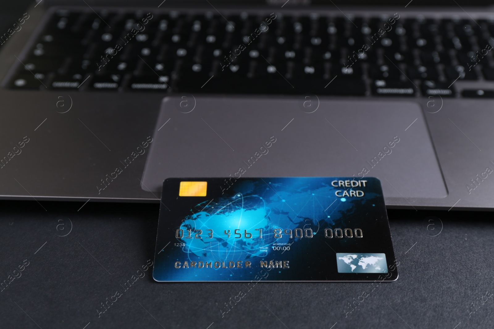 Photo of Credit card and laptop on grey table, closeup