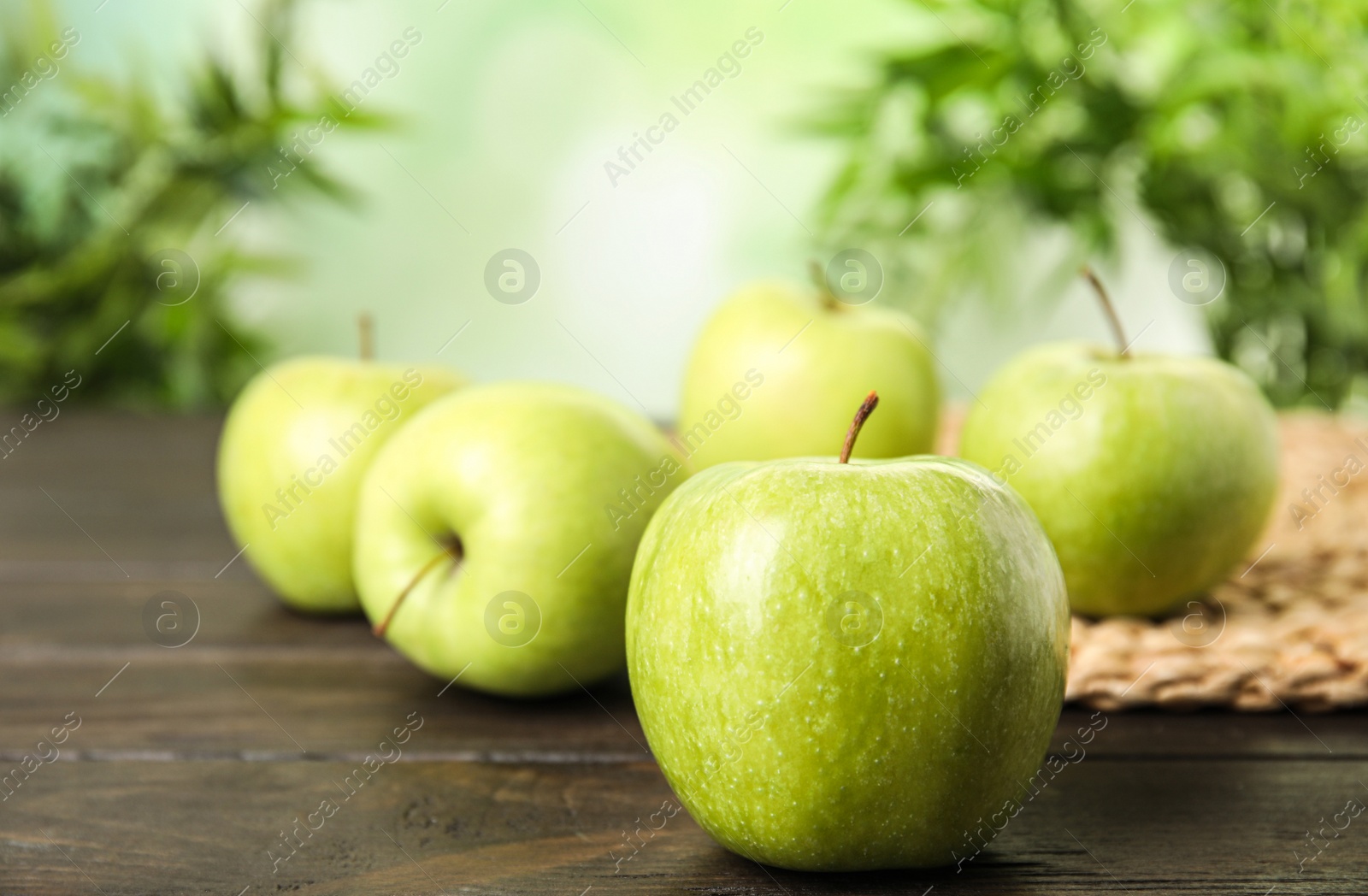 Photo of Fresh ripe green apples on dark wooden table against blurred background, space for text