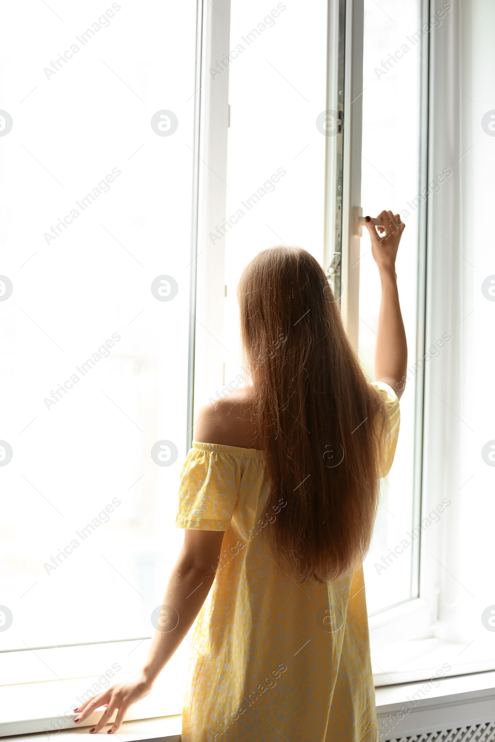 Photo of Young beautiful woman opening big window in room