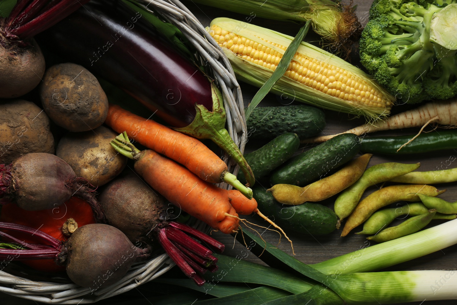 Photo of Basket with different fresh ripe vegetables on wooden table, flat lay. Farmer produce