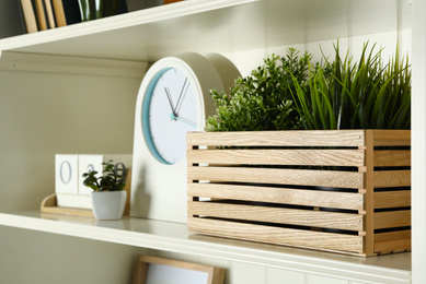 White shelving unit with plants, clock and calendar