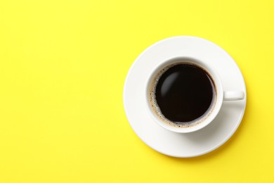 Photo of Cup of aromatic coffee on yellow background, top view. Space for text