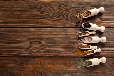 Scoops with different spices on wooden table, flat lay. Space for text