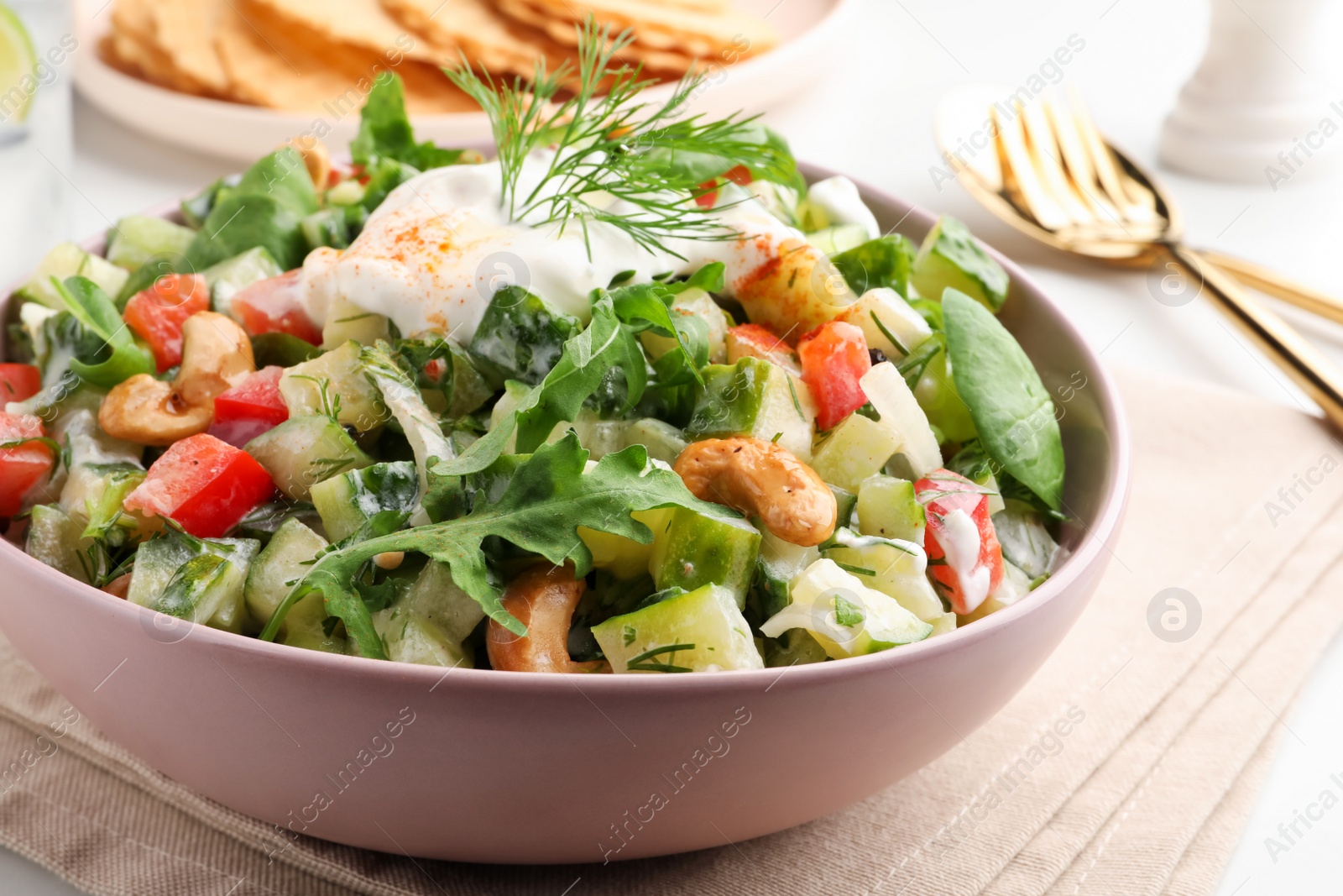 Photo of Bowl of delicious cucumber salad served on white table, closeup