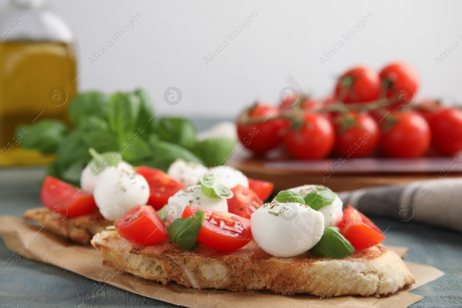Photo of Delicious sandwiches with mozzarella, fresh tomatoes and basil on blue wooden table. Space for text