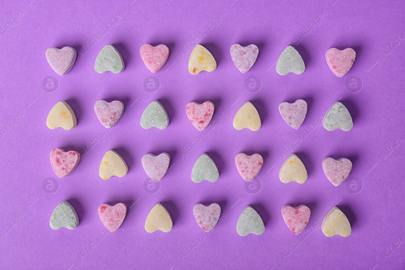 Photo of Small heart shaped candies on color background, flat lay