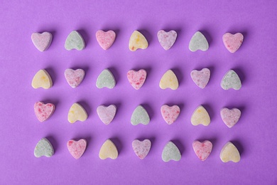 Small heart shaped candies on color background, flat lay