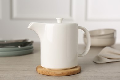 Photo of Ceramic teapot on wooden table. Clean dishware