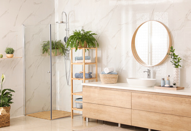 Photo of Stylish bathroom interior with countertop, shower stall and houseplants. Design idea