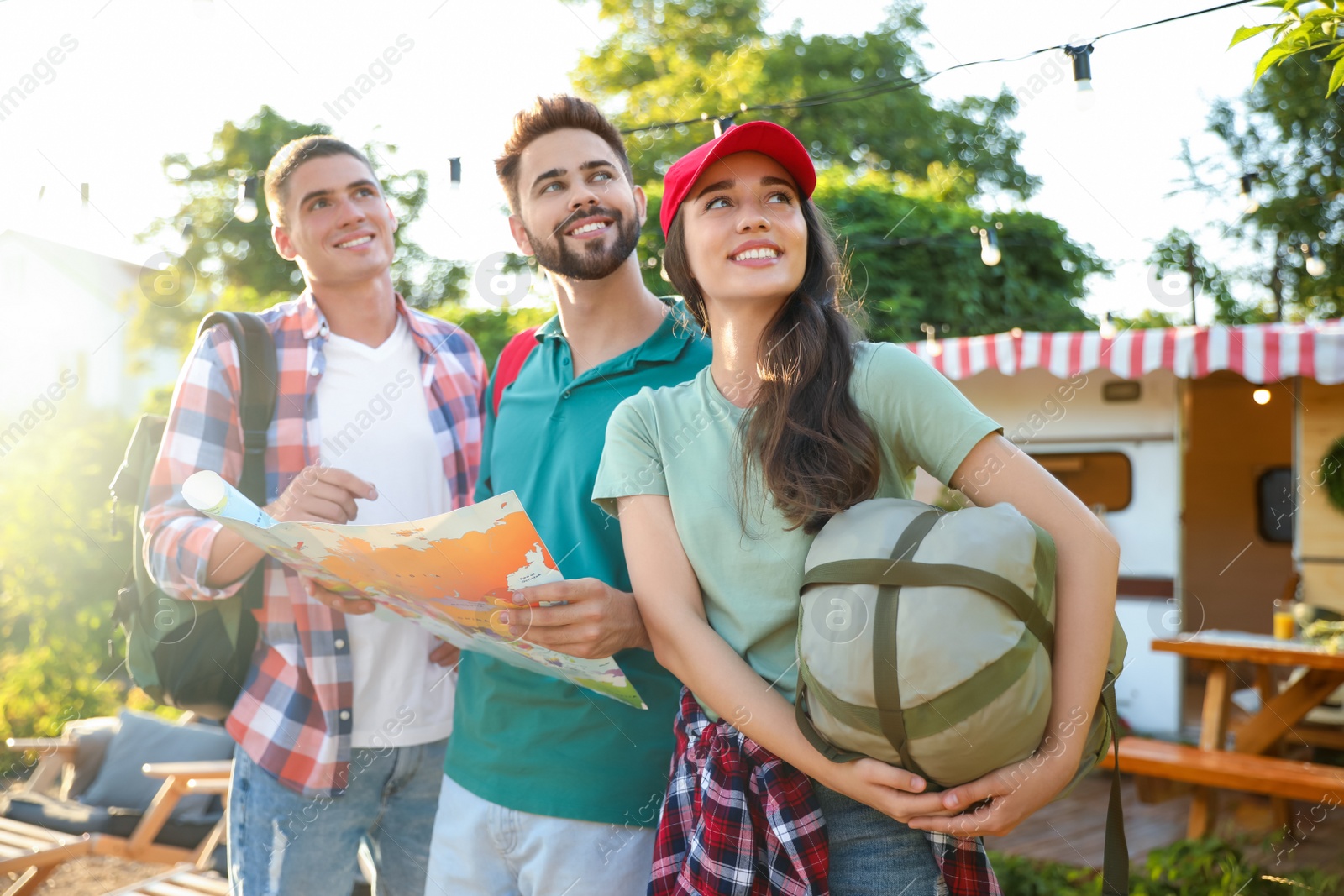 Photo of Young travelers with backpacks and map planning trip outdoors