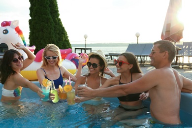 Photo of Group of happy people with refreshing drinks enjoying fun pool party