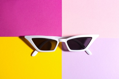 Stylish sunglasses on color background, top view. Summer time