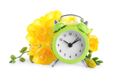 Green alarm clock and spring flowers on white background. Time change