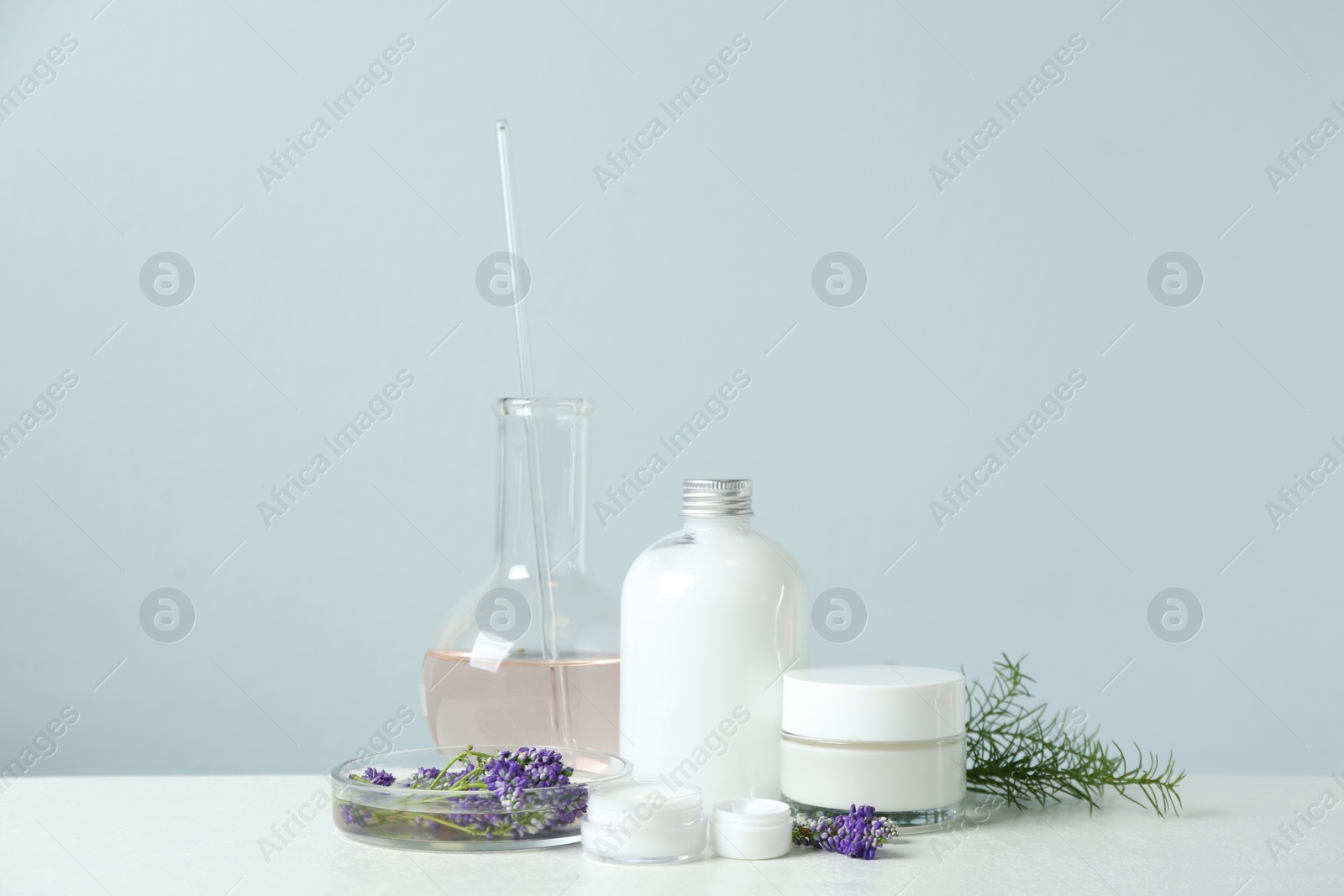 Photo of Herbal cosmetic products, laboratory glassware and ingredients on white table