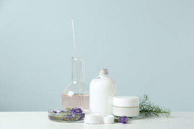 Photo of Herbal cosmetic products, laboratory glassware and ingredients on white table