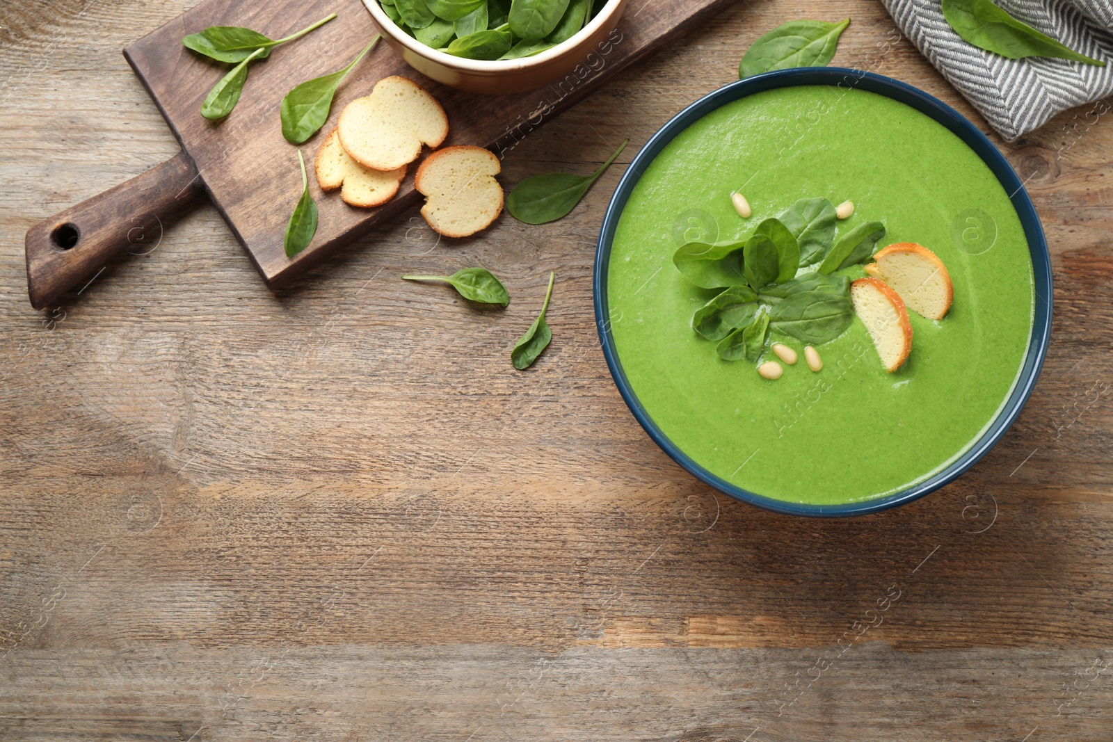 Photo of Flat lay composition with fresh green healthy spinach soup on wooden table, space for text