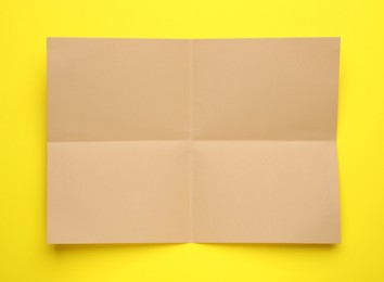 Sheet of brown paper on yellow background, top view