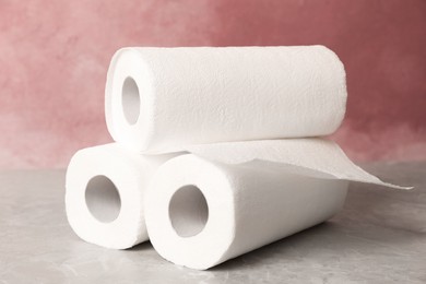 Photo of Rolls of white paper towels on grey table near pink wall