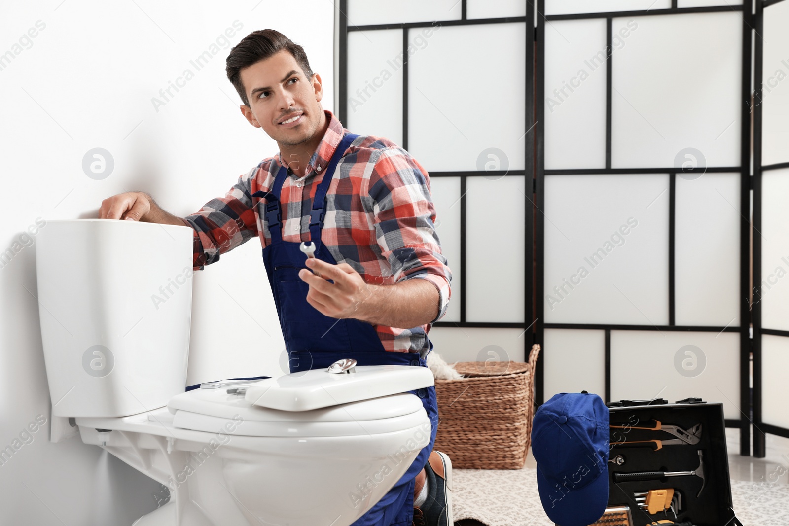 Photo of Professional plumber working with toilet bowl in bathroom