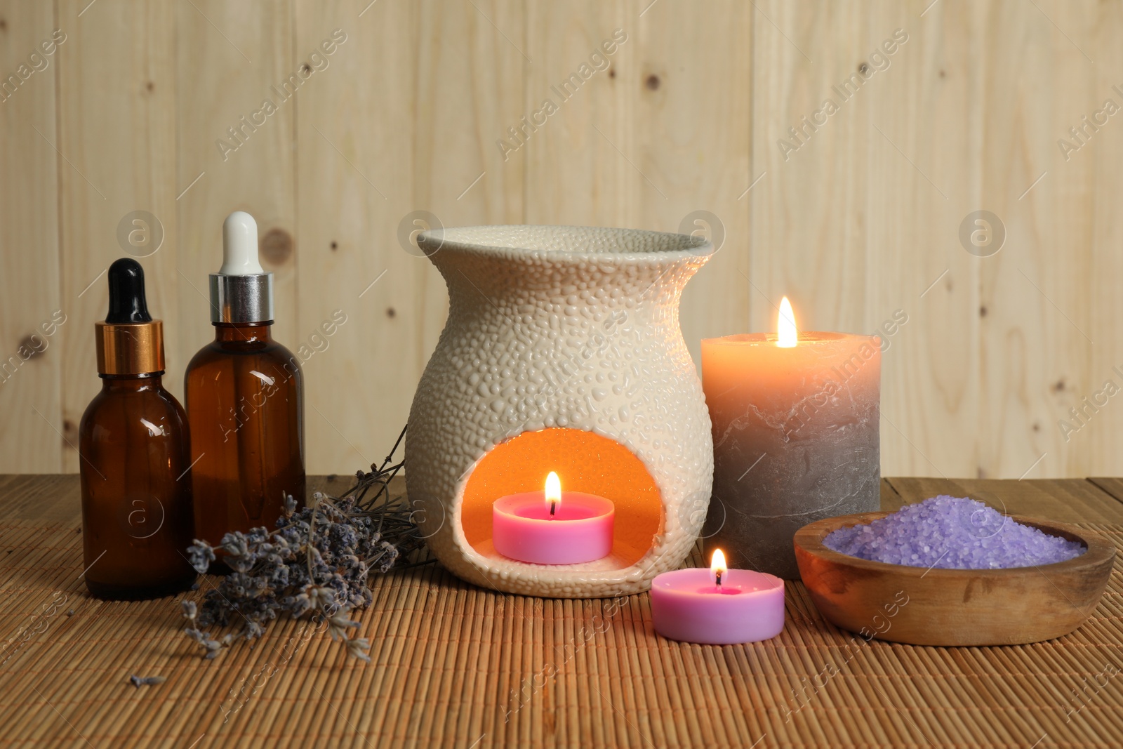 Photo of Aromatherapy. Scented candles, bottles, lavender and sea salt on bamboo mat