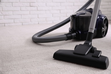 Photo of Modern vacuum cleaner on carpet indoors, closeup. Space for text