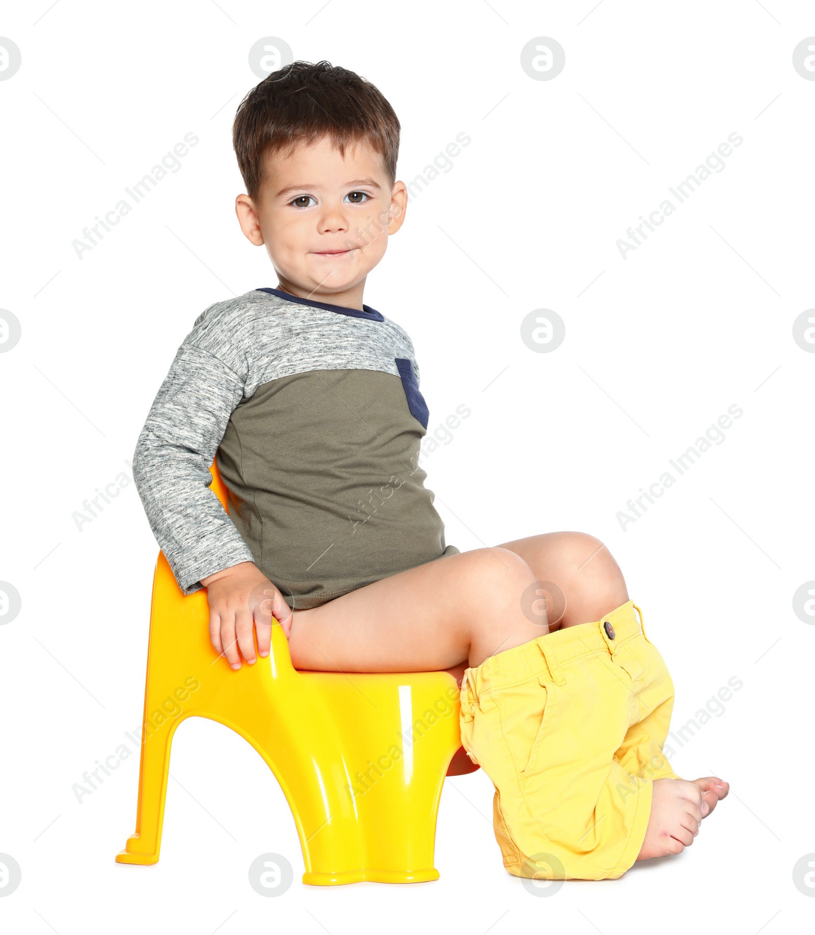 Photo of Portrait of little boy sitting on potty against white background