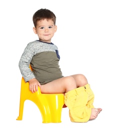 Portrait of little boy sitting on potty against white background