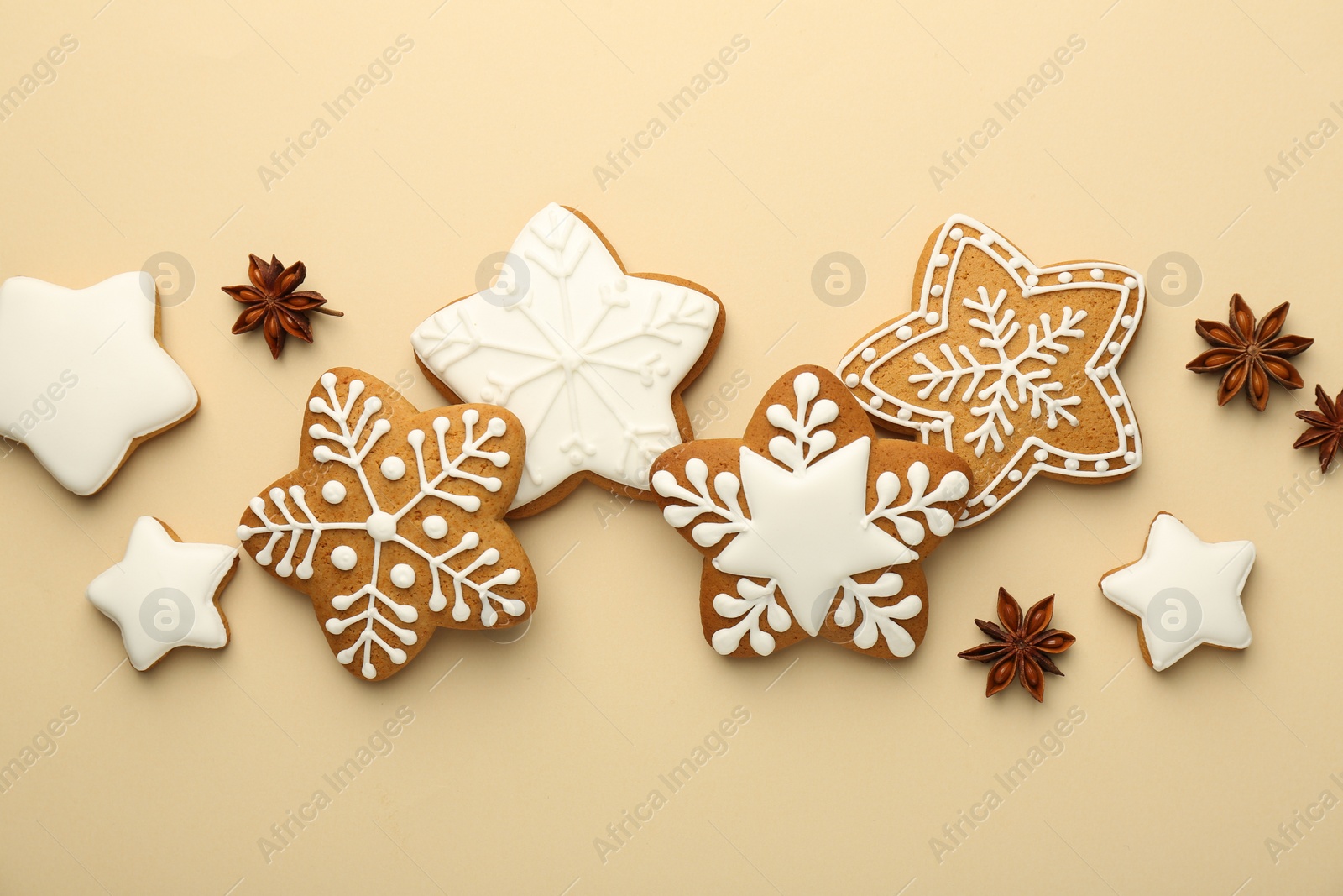 Photo of Tasty Christmas cookies with icing and anise stars on beige background, flat lay