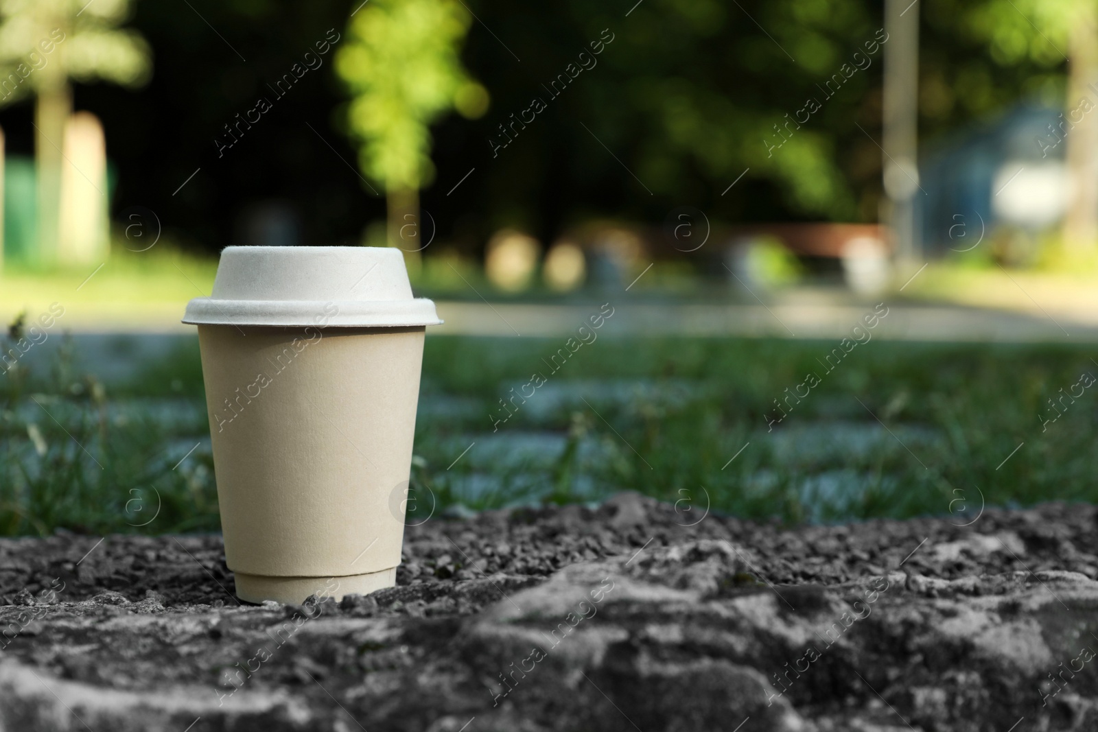 Photo of Cardboard takeaway coffee cup with lid on stone surface outdoors, space for text