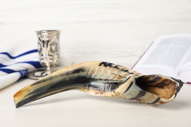 Photo of Shofar and other Rosh Hashanah holiday attributes on white wooden table