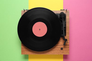 Photo of Modern turntable with vinyl record on color background, top view