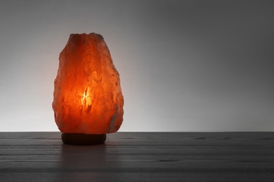 Photo of Himalayan salt lamp on table against dark background