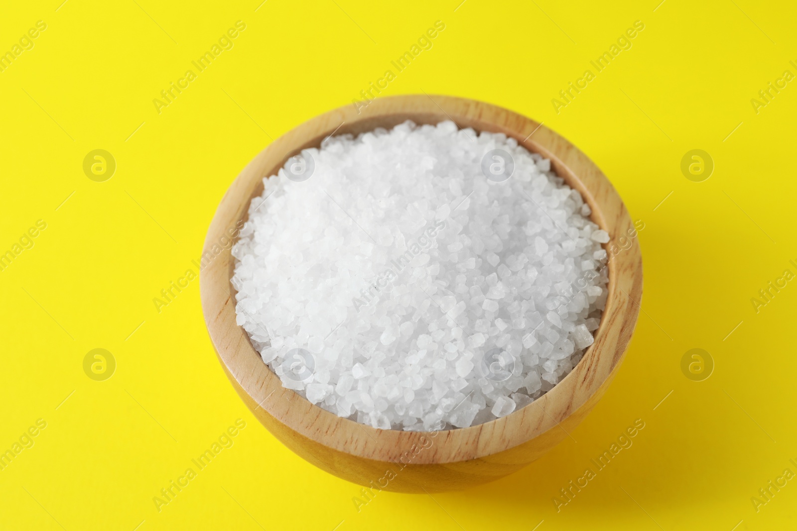 Photo of Organic white salt in bowl on yellow background