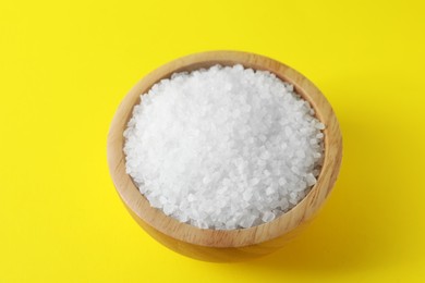 Organic white salt in bowl on yellow background