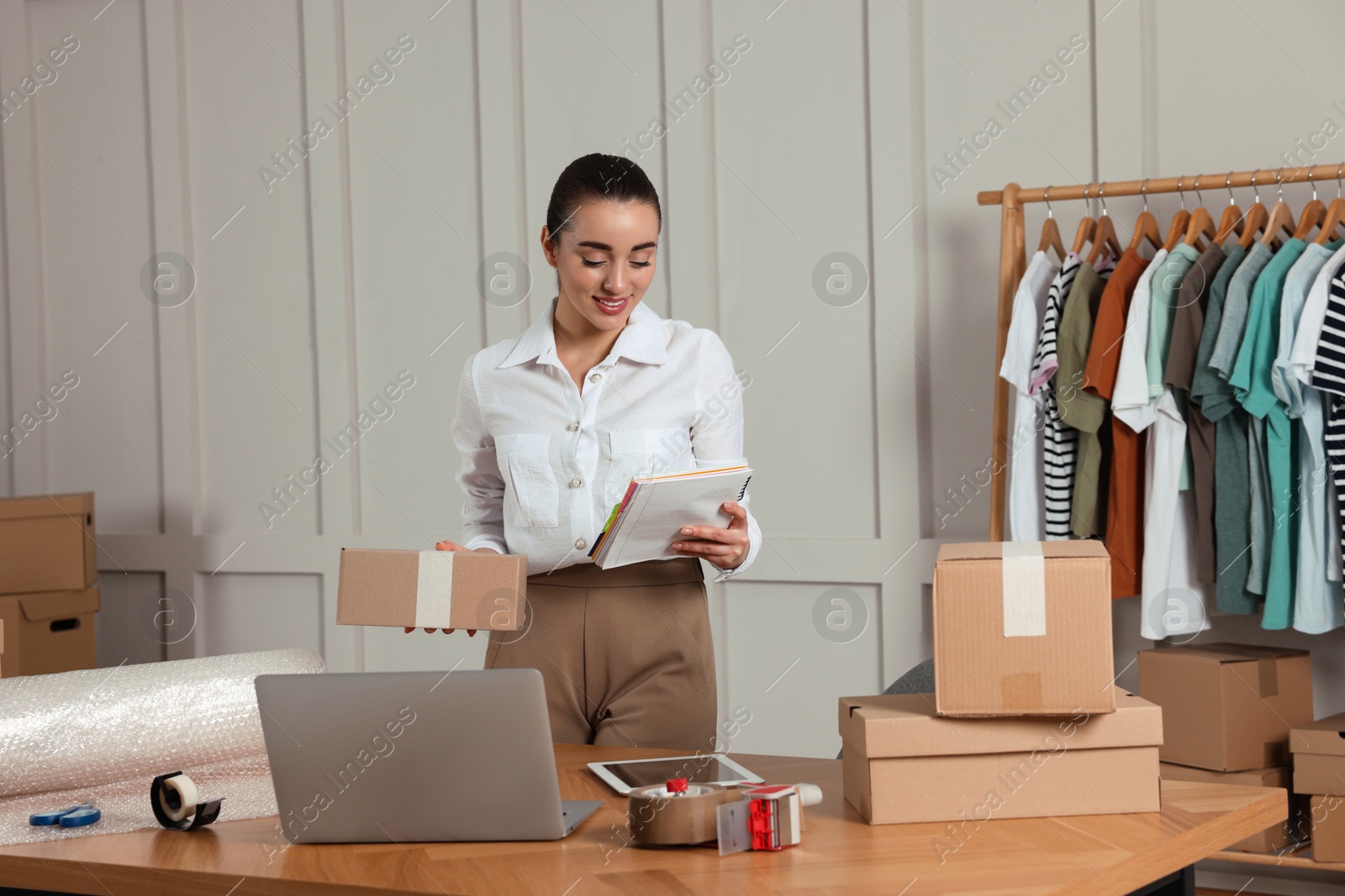 Photo of Seller with notebook and parcel in office. Online store