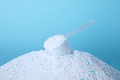 Pile of laundry detergent and measuring scoop against blue background