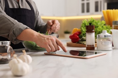 Photo of Man using tablet while cooking at countertop in kitchen, closeup